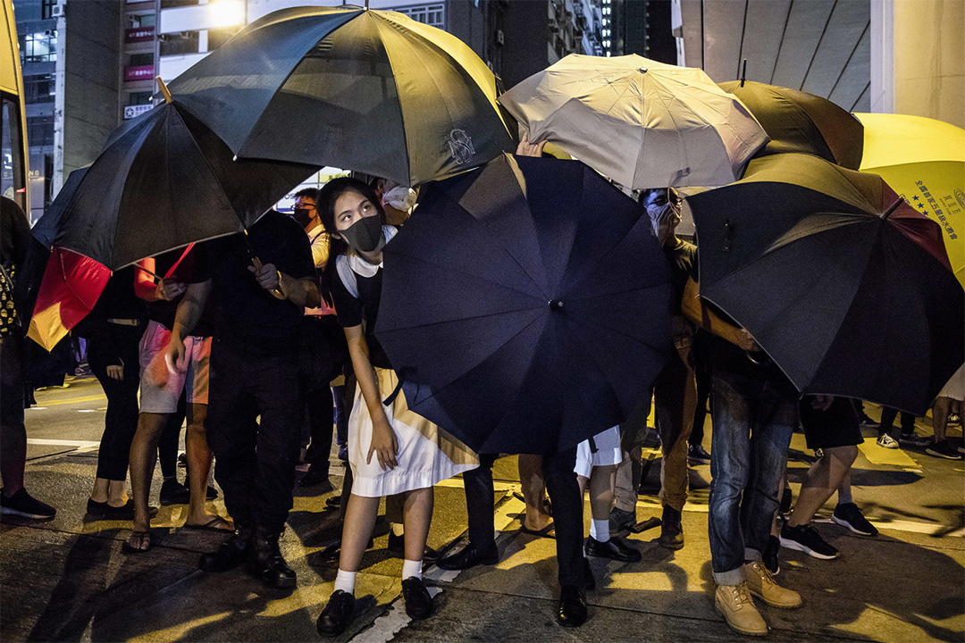 2019年9月3日，一名穿著校服的示威者在太子警署门外示威，在雨伞阵内向外眺望。