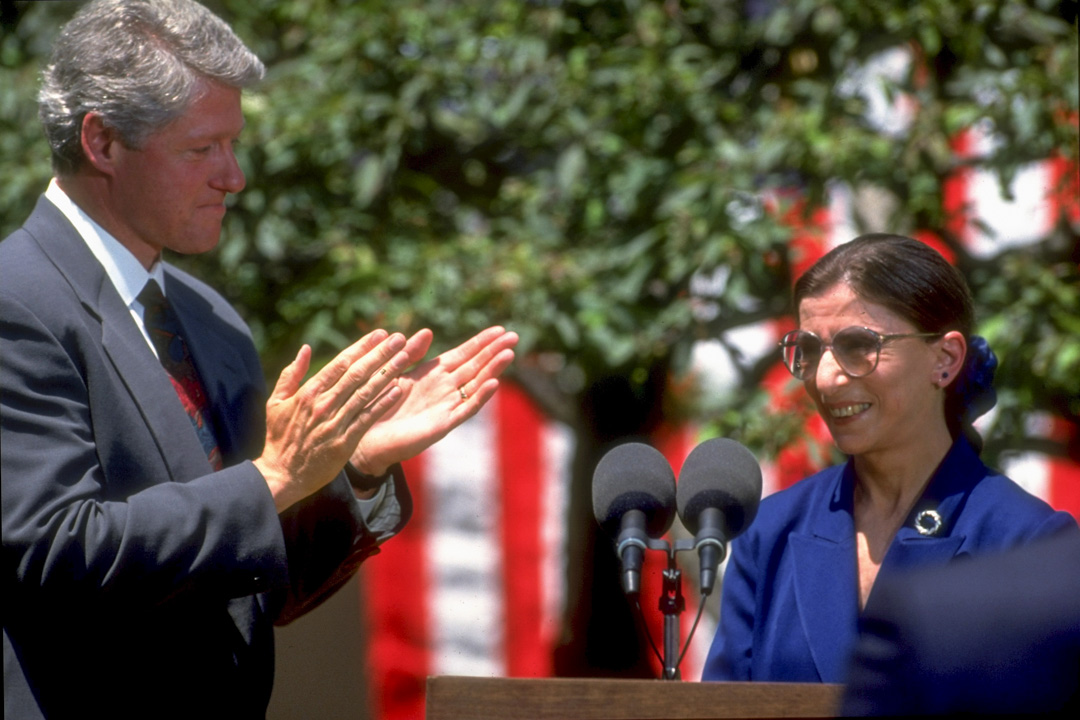 1993年6月14日，新上任美国最高法院法官的金斯堡（Ruth Bader Ginsburg）发表演说后，美国总统克林顿在旁鼓掌。 