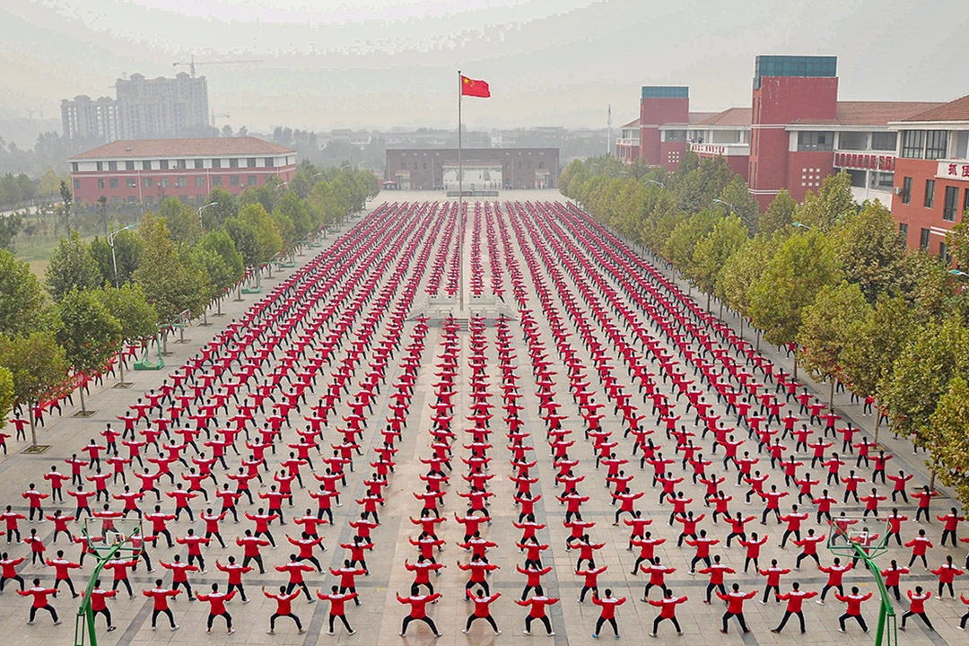 2015年10月18日中国河南省，中国国旗下学生们在高中的操场上练习太极拳。