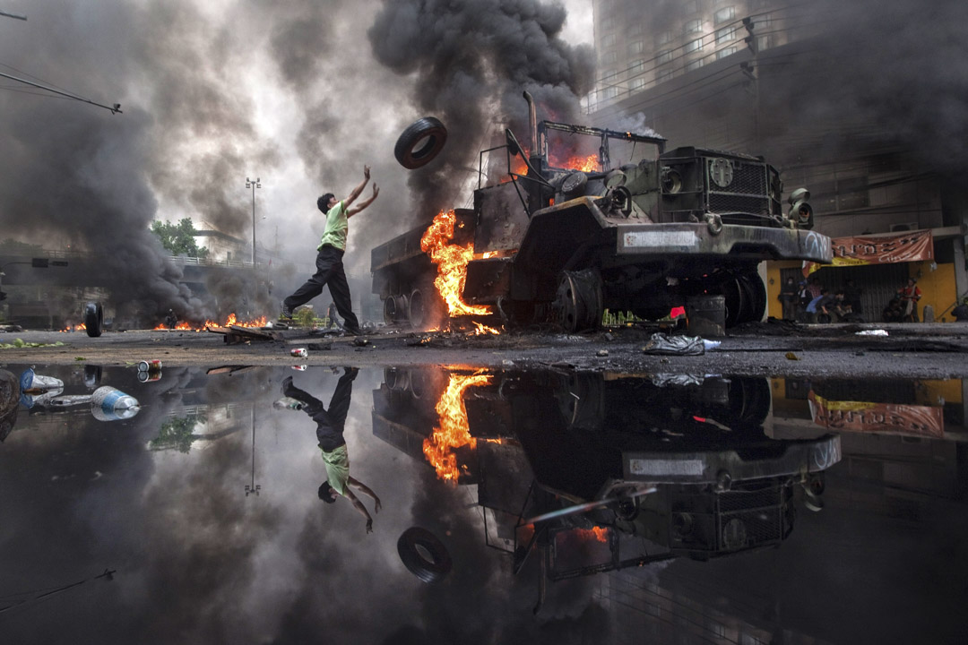 2010年5月16日曼谷，反政府抗議者紅衫軍投擲輪胎往被燒的卡車。