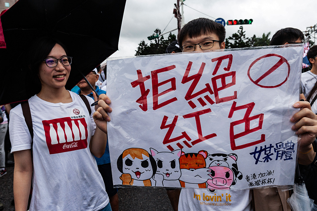 2019年6月23日台北，抗议者站在大雨中举着标语示威。