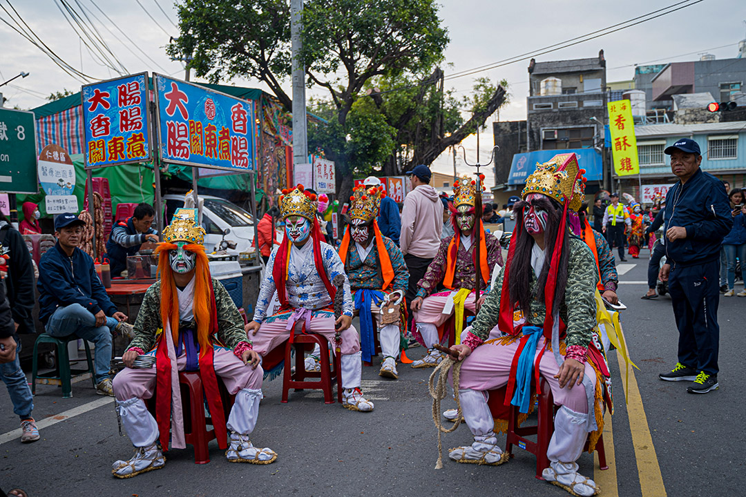 一群官將首在途中稍事休息。祭典所及之處，都會吸引攤販聚集，形成流動的小型夜市。