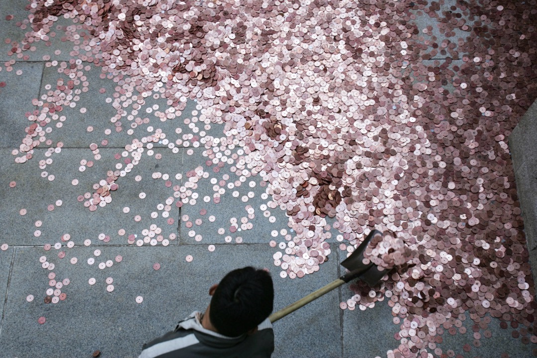 2007年，北京，白雲觀的一位員工在清理市民為祈福拋出的硬幣。