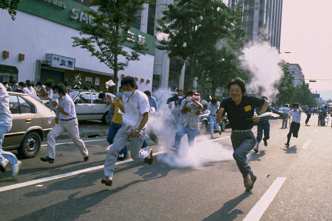 1987年6月26日，首爾街頭的示威遊行，學生抗議者在催淚彈中奔跑。