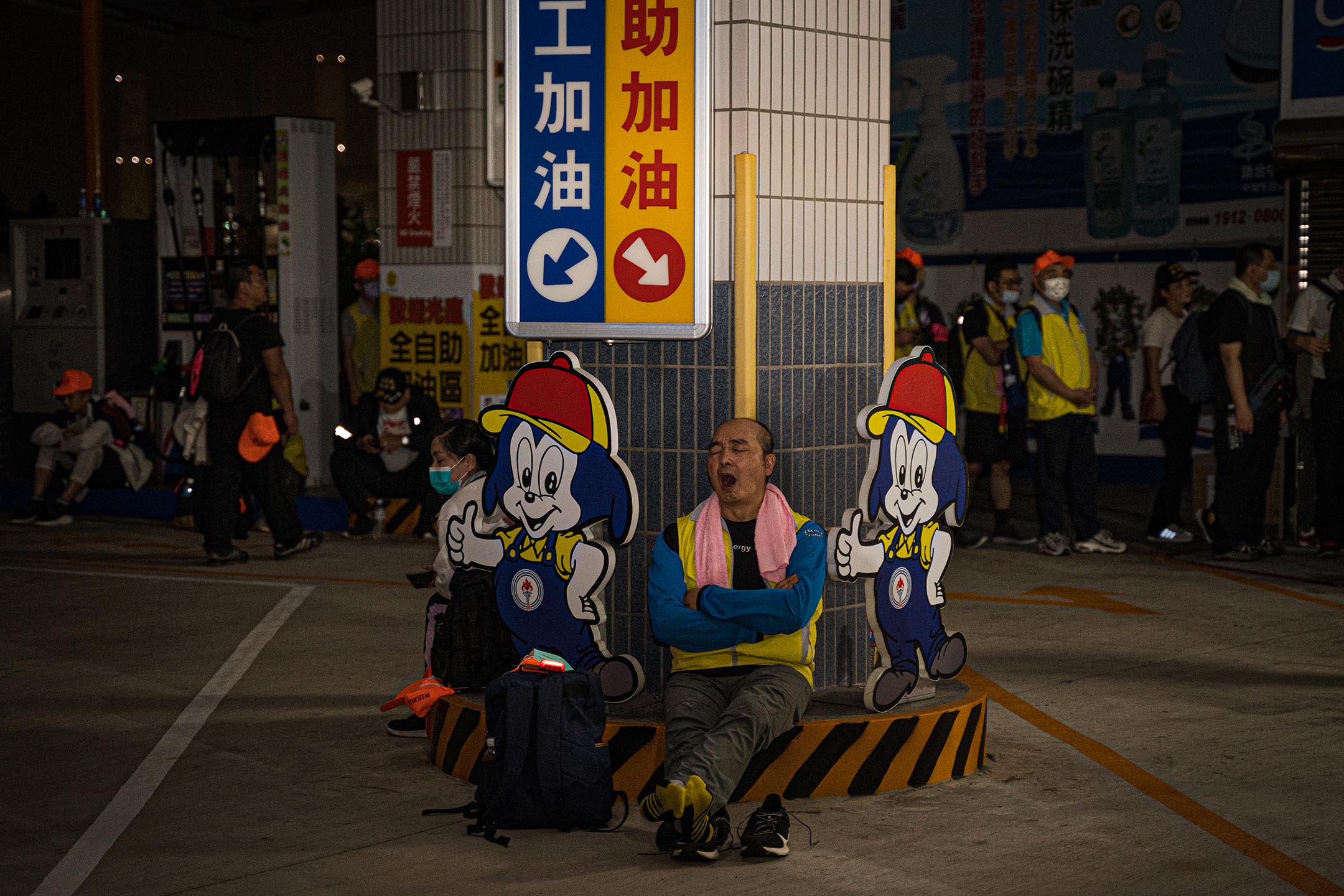 在少有民宅的公路路段上，加油站是信众如厕、补给、休息的重要据点。一名信众在加油站就地休息。