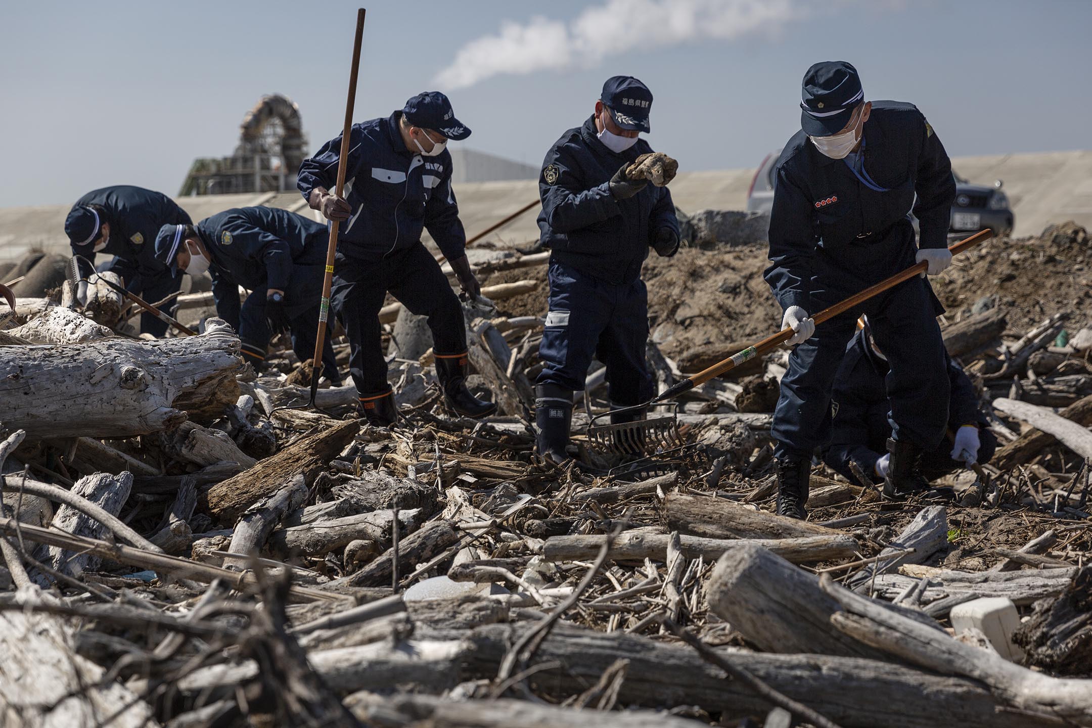 2021年3月11日，日本福岛县浪江町，警员在海边搜索十年前福岛核电厂爆炸事故中失踪者的遗体。