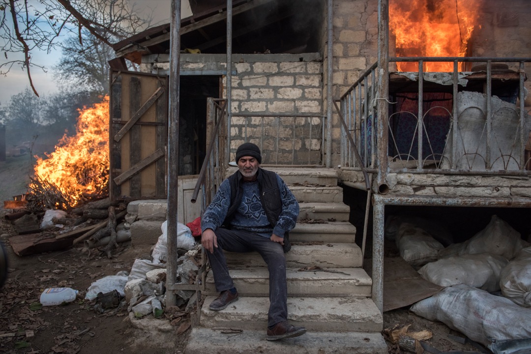 2020年11月25日，纳戈尔诺-卡拉巴赫（Nagorno-Karabakh）小镇 Karegakh，男子 Areg 坐在一所正在燃烧的建筑物前。