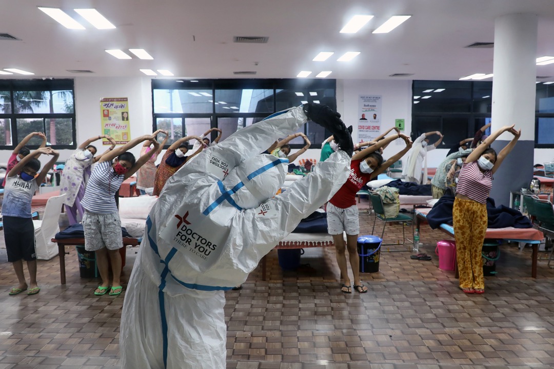 2020年7月30日，印度首都新德里市郊的村落，一名医护人员为女性病房内的新冠病毒轻症患者带领伸展训练。