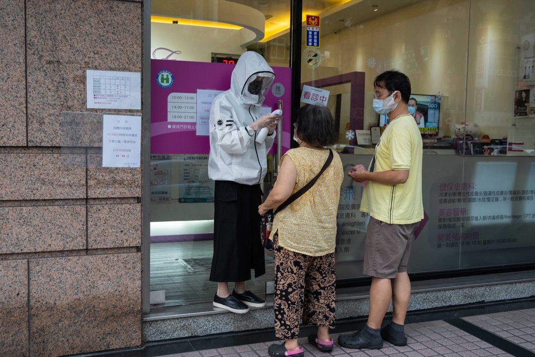 2021年5月27日，台北街头，一名店员为顾客量度体温。