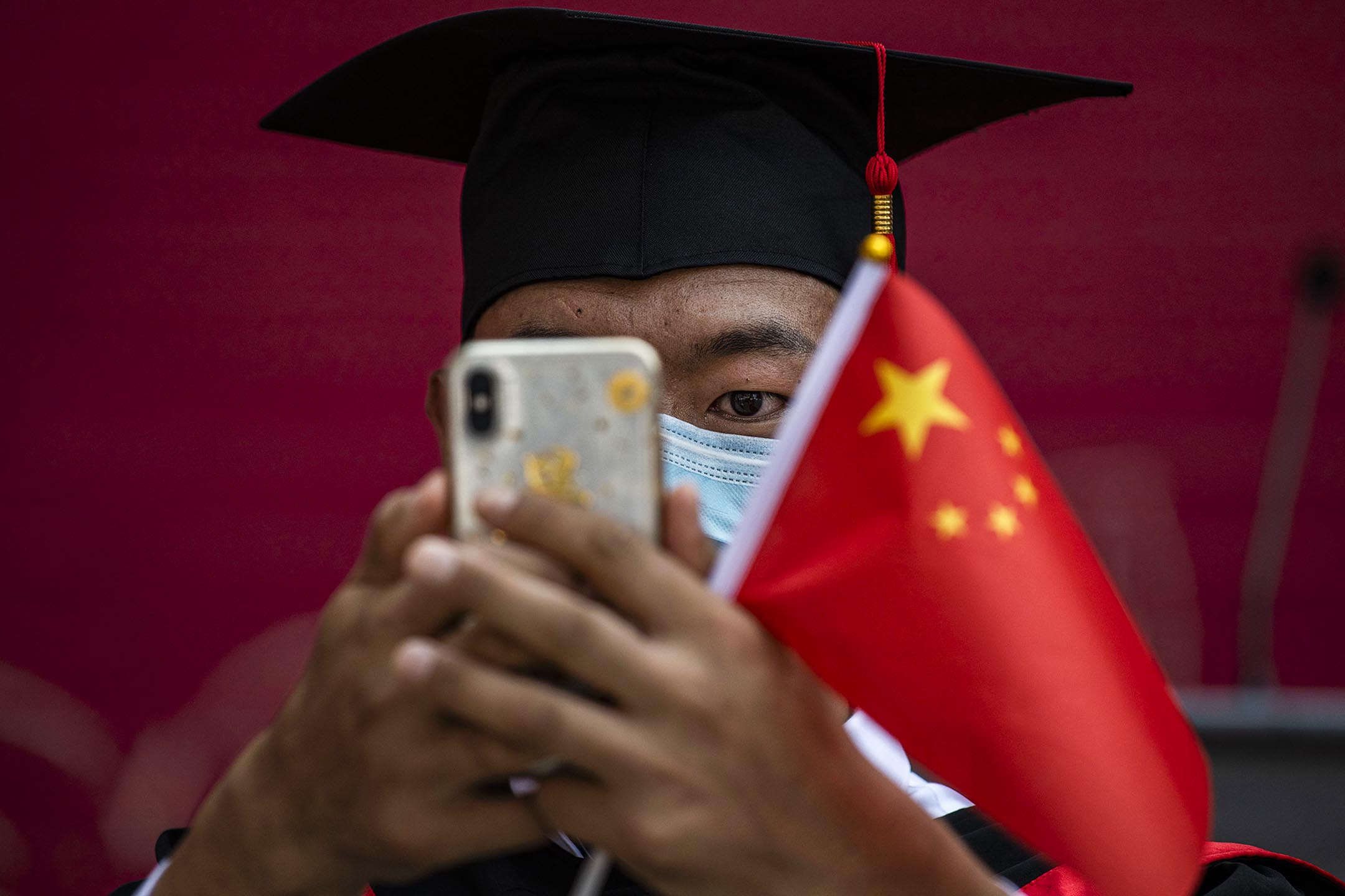 2020年6月30日在中国北京，中国人民大学的学生拿著一面国旗参加毕业典礼。