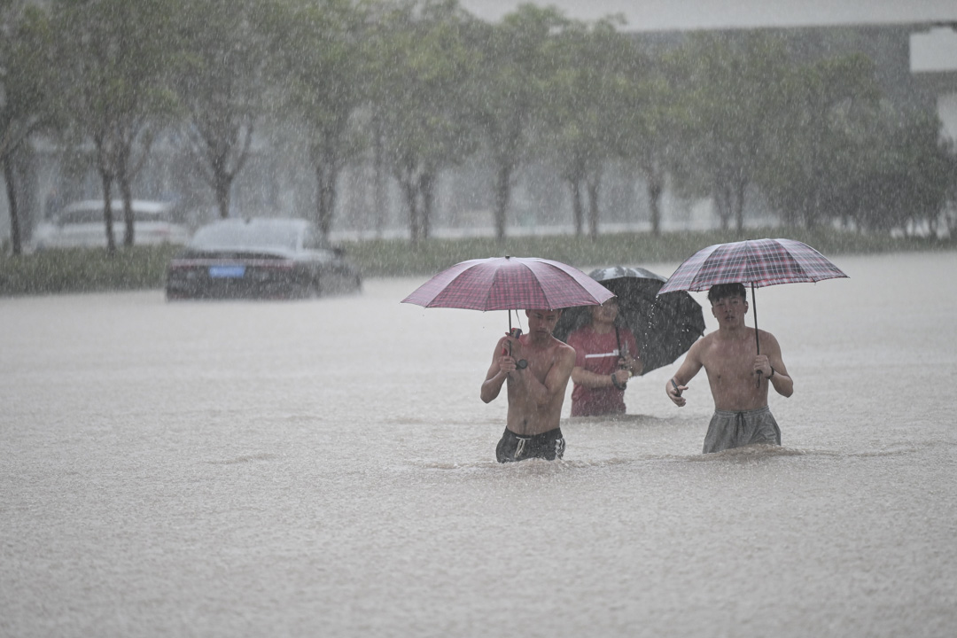 2021年7月20日，河南省郑州市，人们在郑州火车站附近的洪水中行走。