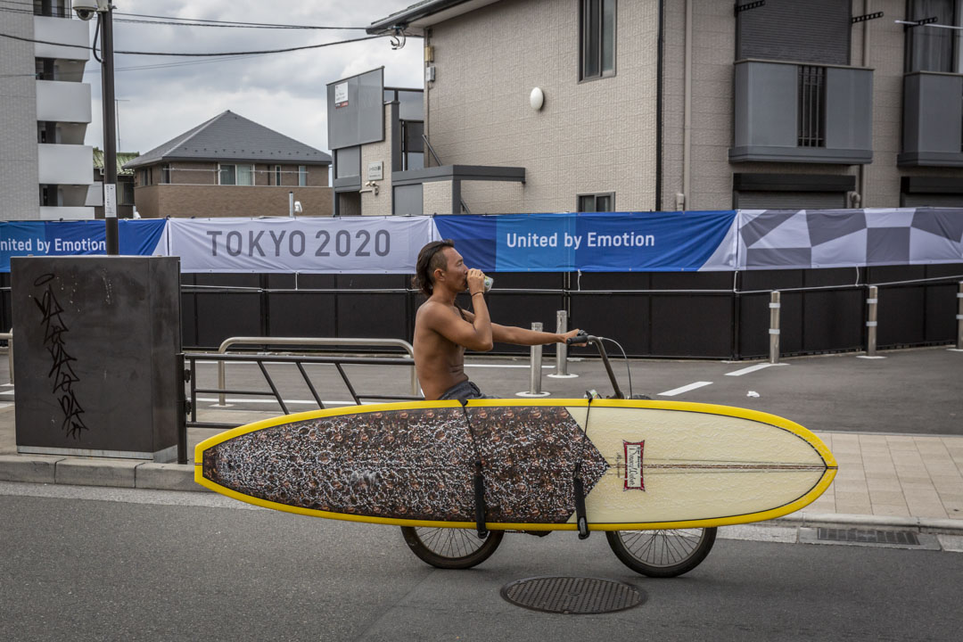 2021年6月28日日本藤泽市，一名冲浪者骑车经过东京奥运会的宣传横幅。