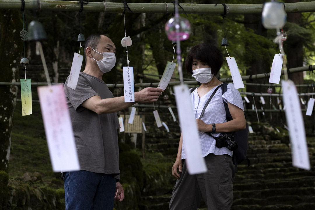 2021年7月13日，丹波一名戴着口罩的市民在青垣寺阅读印有人们愿望的风铃纸条。