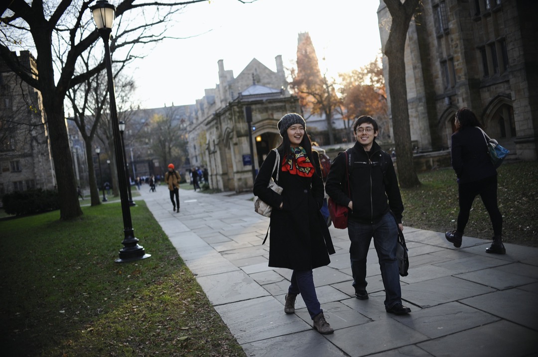 一位二年级中国留学生在美国耶鲁大学与一位本地生同学散步。