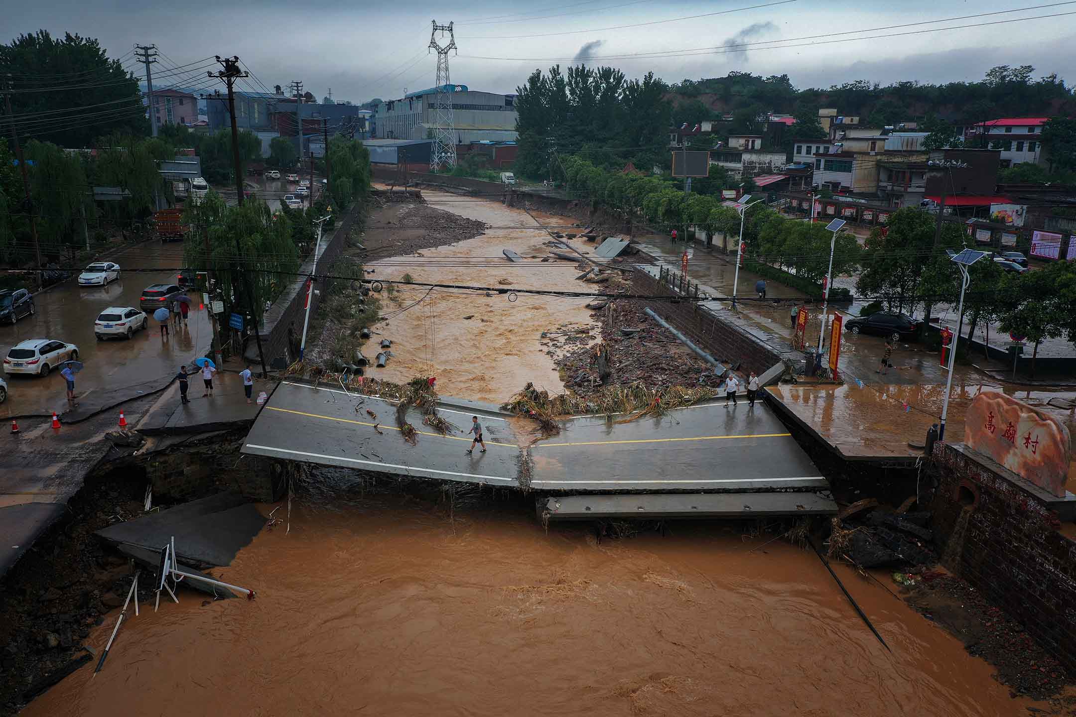 2021年7月21日中国河南省巩义市，暴雨过后，人们走在受损的桥上。