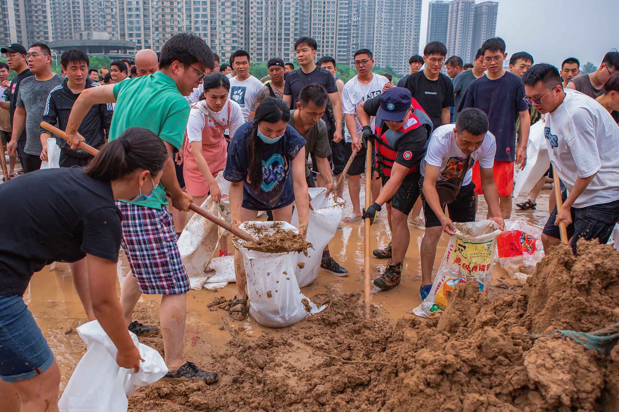 2021年7月23日中國新鄉，救援隊和居民使用沙袋建造圍堰，防止暴雨後的洪水。