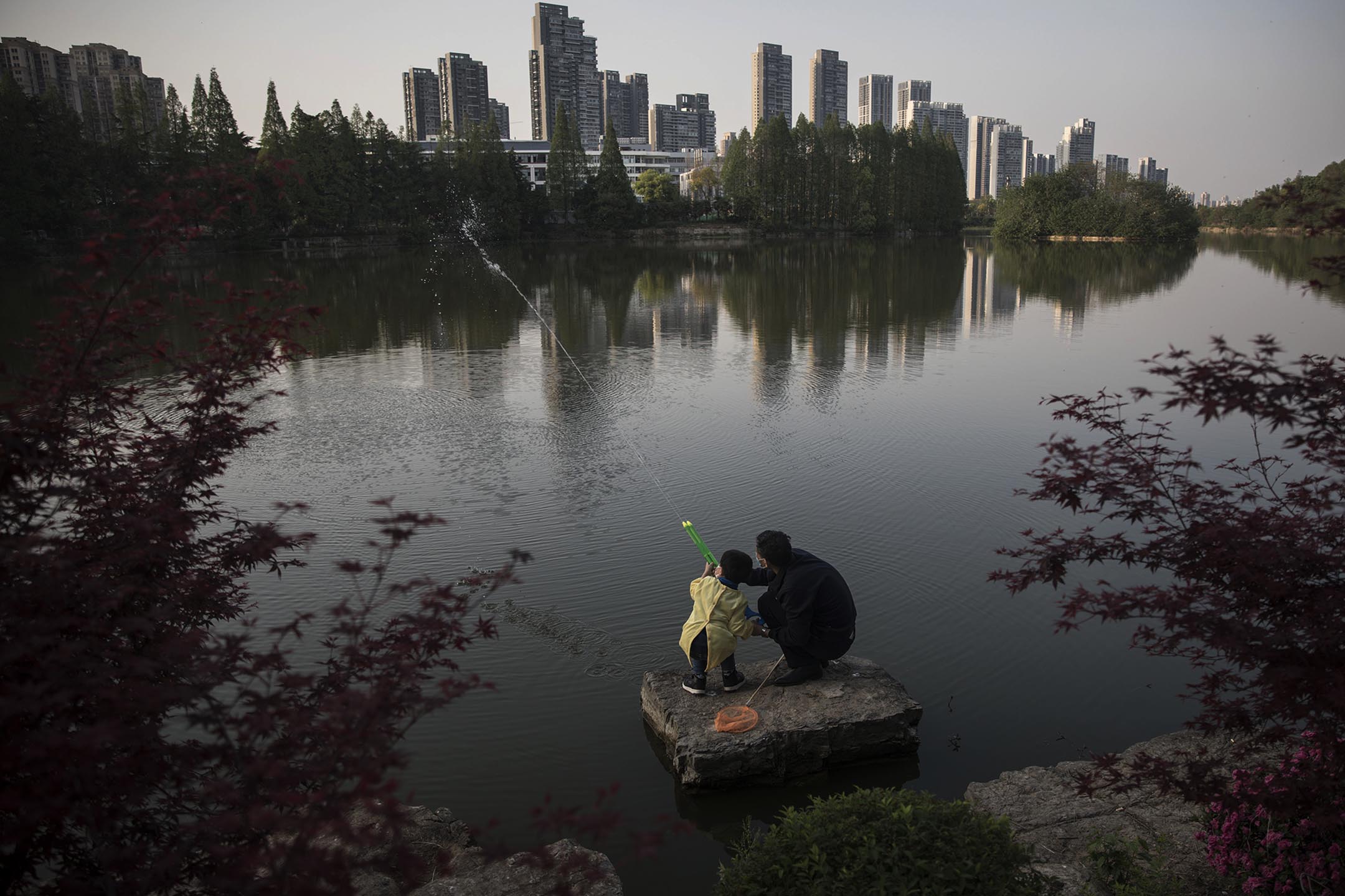 2020年4月9日中国武汉，一个男孩和他的爷爷在公园玩水枪。