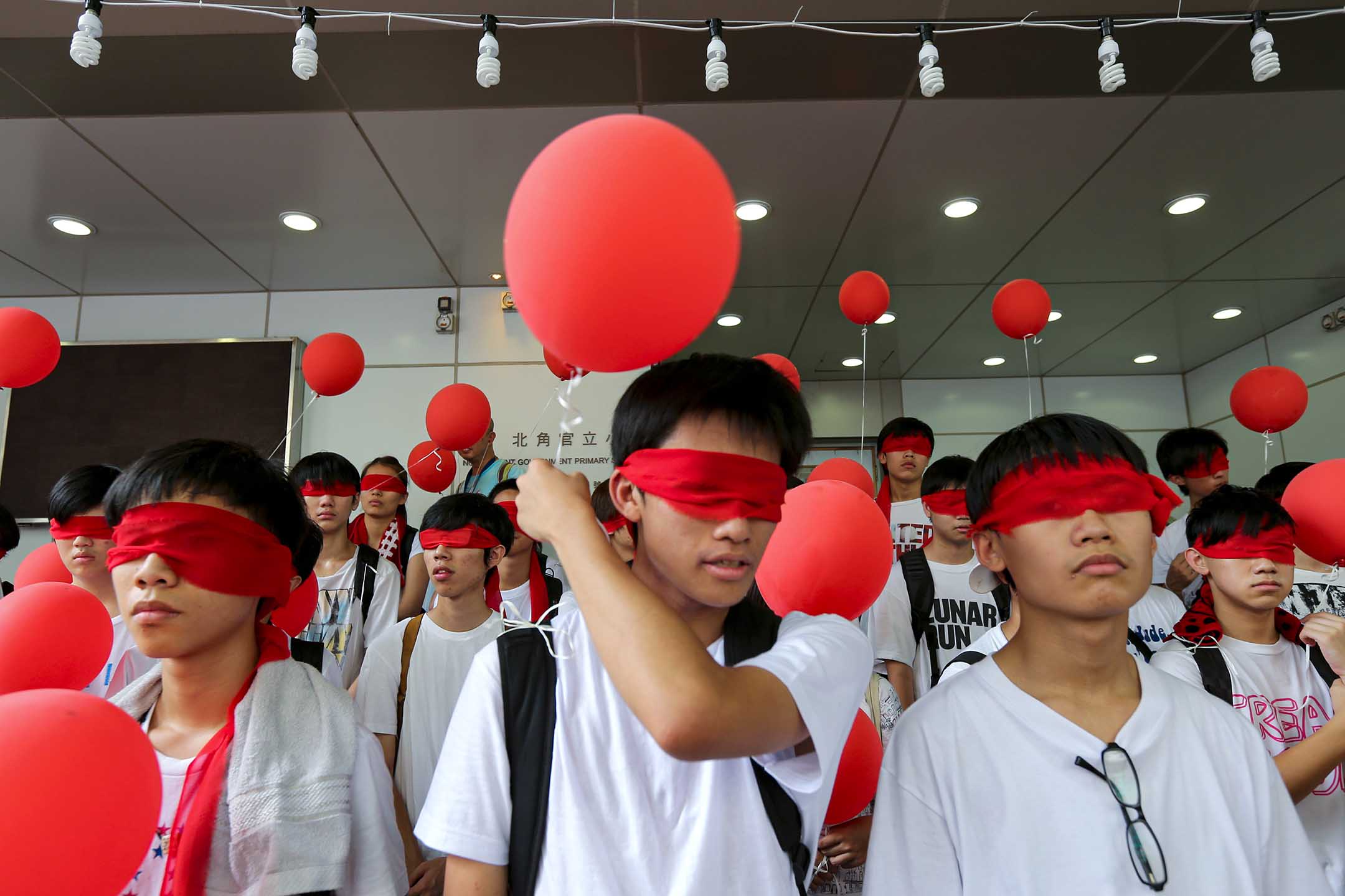 2012年8月28日，示威者在北角官立小学外戴著红色眼罩拿著气球，抗议国民教育。