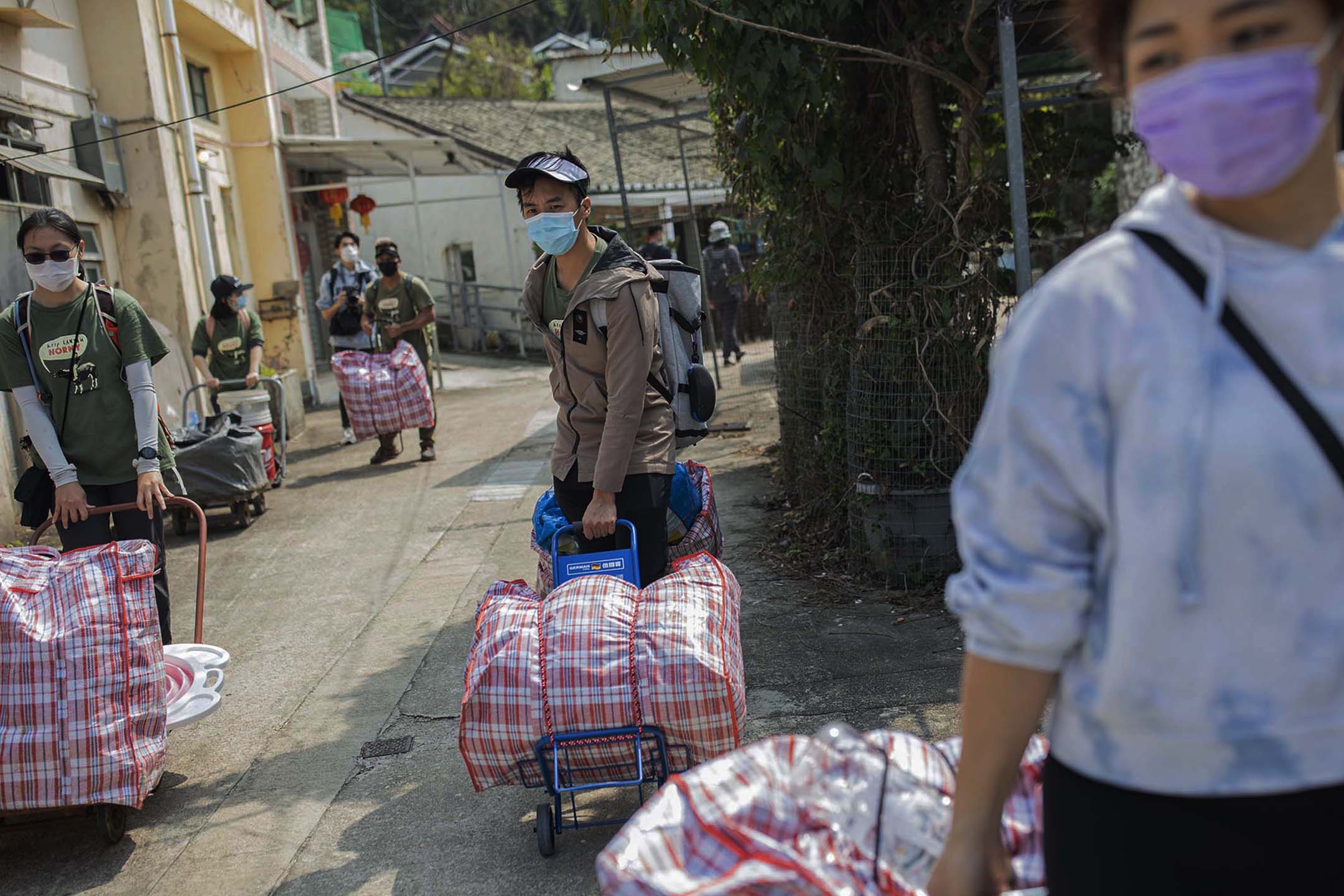 义工们早上从野外割了鲜草，而后卖力把草抬下船拉上山。