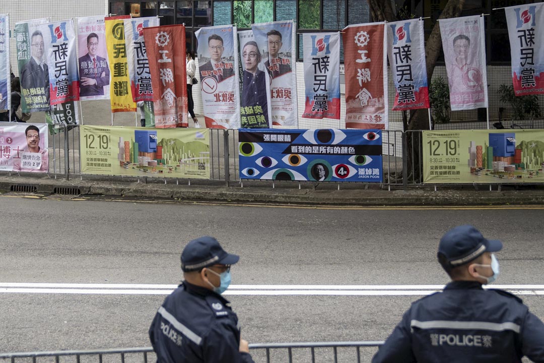 2021年12月19日，港島東選區，康怡花園馬路旁插著多支立法會候選人的旗幟，附近有警員駐守。