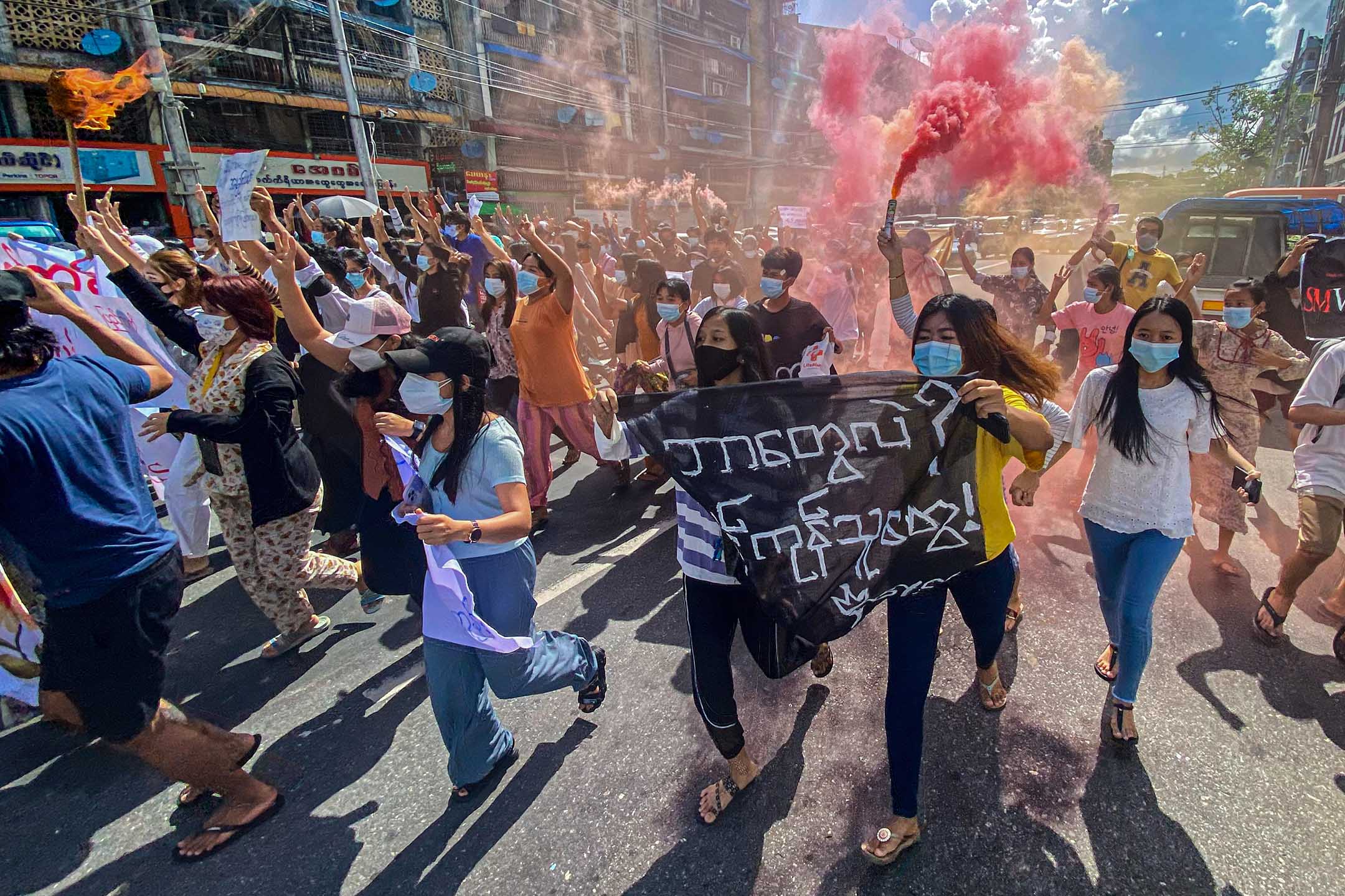 2021年7月14日缅甸仰光，仰光举行的反政变示威的游行中，妇女手持横幅和紧急信号棒。