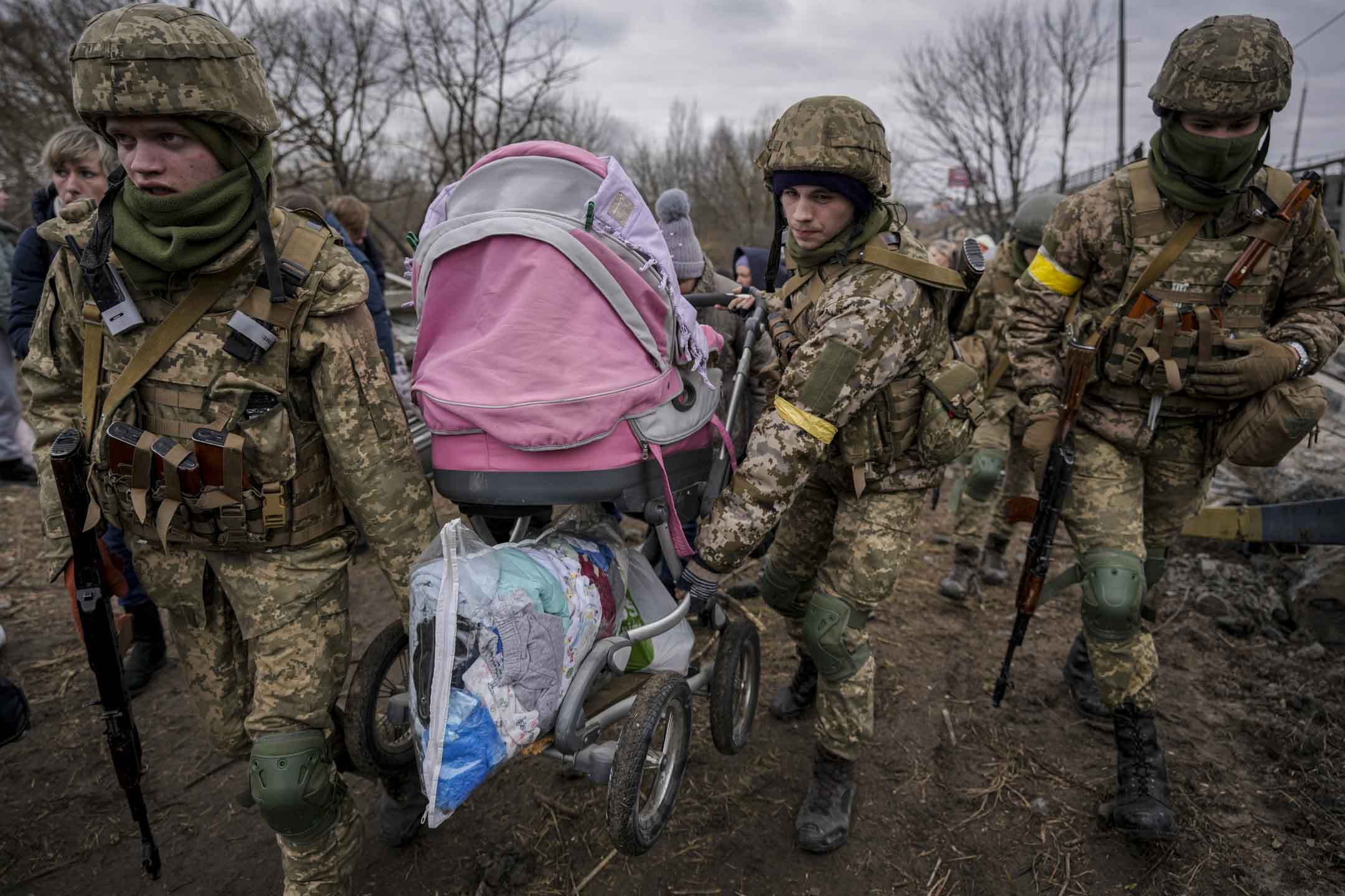 2022年3月5日，烏克蘭軍人在伊爾平鎮一座被俄羅斯空襲摧毀的小路上，兩名軍人協助嬰兒車搬離現場。