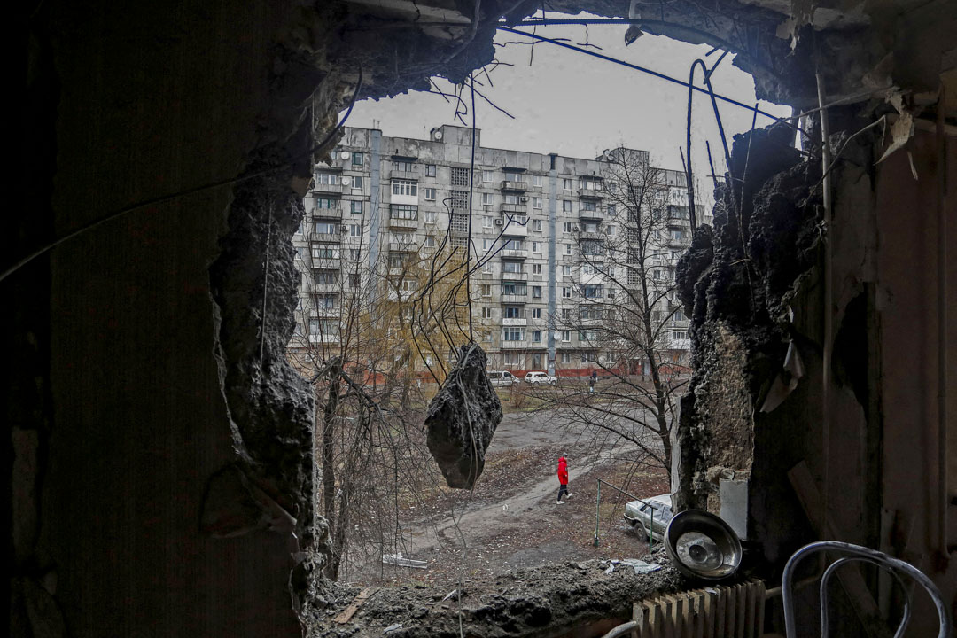 2022年3月2日，乌克兰东部顿涅茨克地区，一座民居的墙壁被炮击炸破，一名男子在大楼外走过。