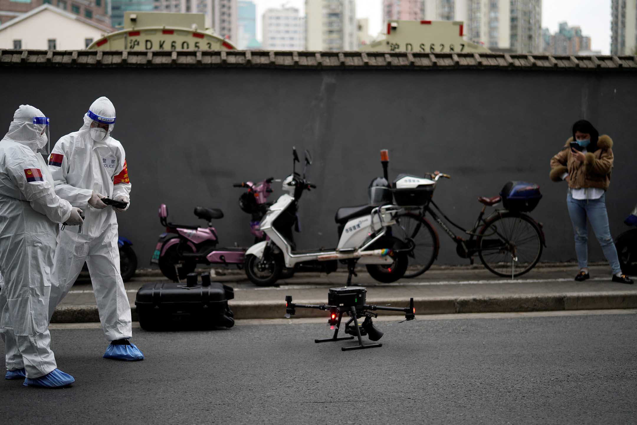 2022年3月30日，上海，身穿防护衣的警察操作一架带有扬声器的无人机，提醒居民采取防疫措施。