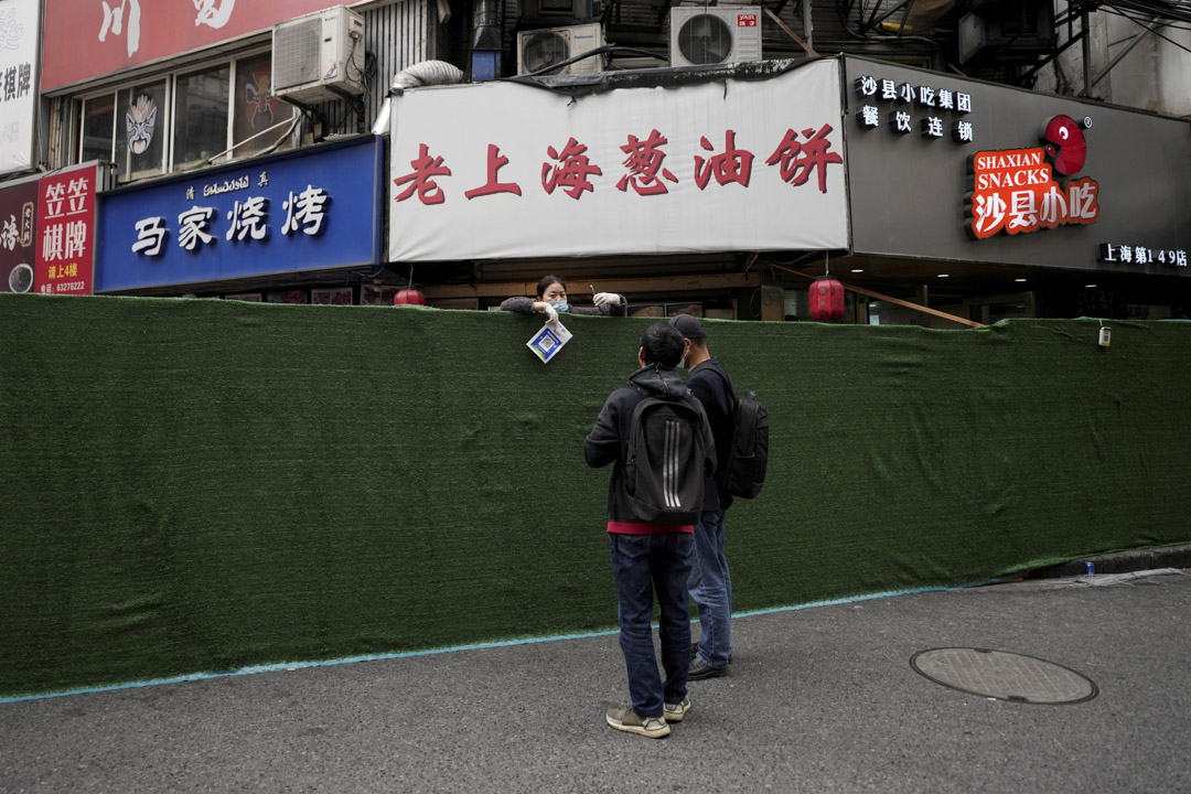 2022年3月31日，上海为COVID-19的传播而进行的两阶段封锁，一名食品供应商手持有一个二维码，在障碍物上替客人付款。