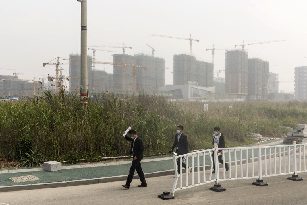 2020年4月，中国宁波市杭州湾新区，三名地产从业员在兴建中的住宅前走过。