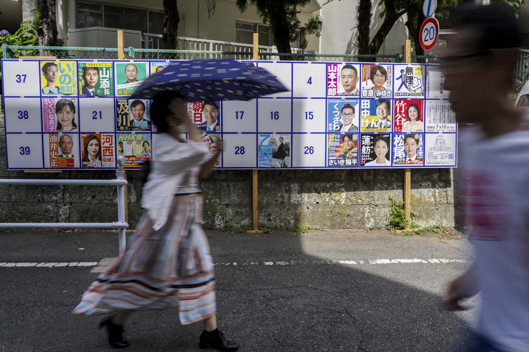 2022年7月10日，东京行人走过一个展示日本参议院选举候选人海报的布告牌。