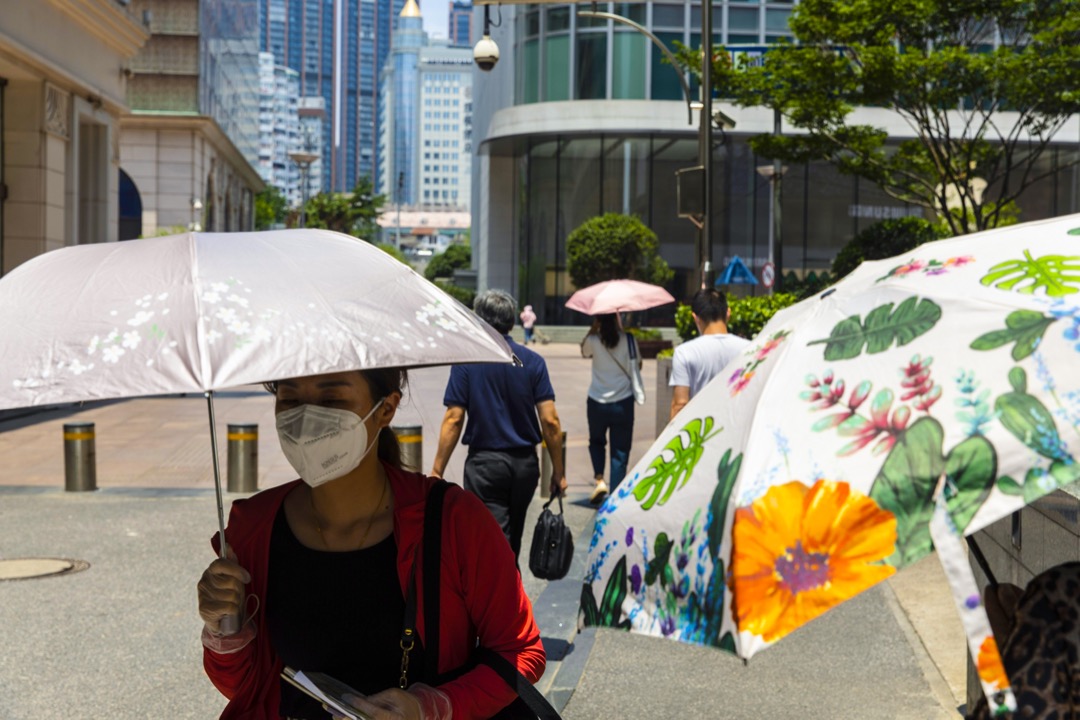 2022年7月14日，中国上海，市民用伞遮挡太阳光。