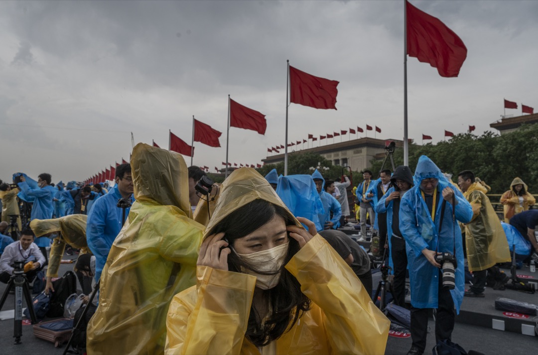 2021年7月1日，中国首都北京，天安门广场举行共产党创党100周年庆祝仪式之际突然下雨，记者们赶忙穿上雨衣。