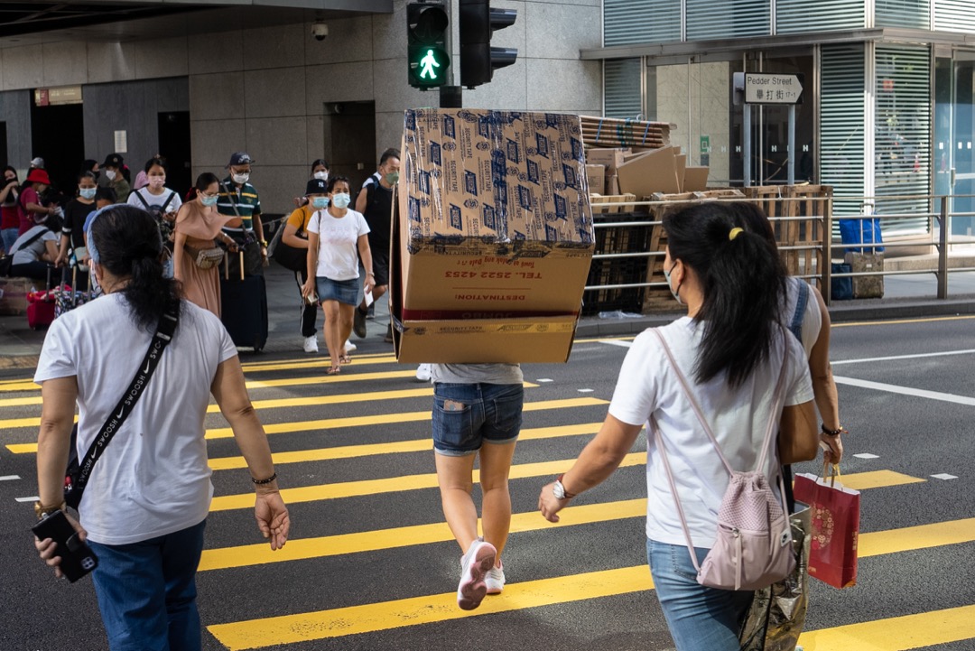 香港，一名移工抬著一个纸箱过马路。