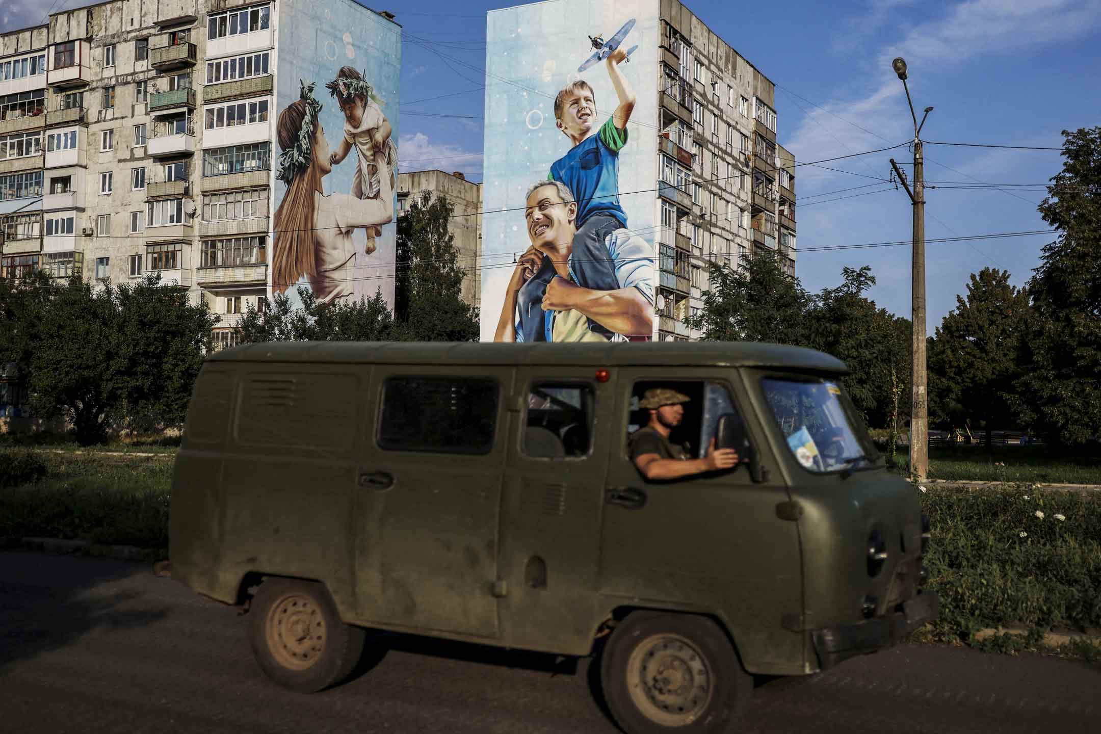 2022年8月14日，烏克蘭頓涅茨克地區，烏克蘭軍人開車經過巴赫穆特受損的建築物。