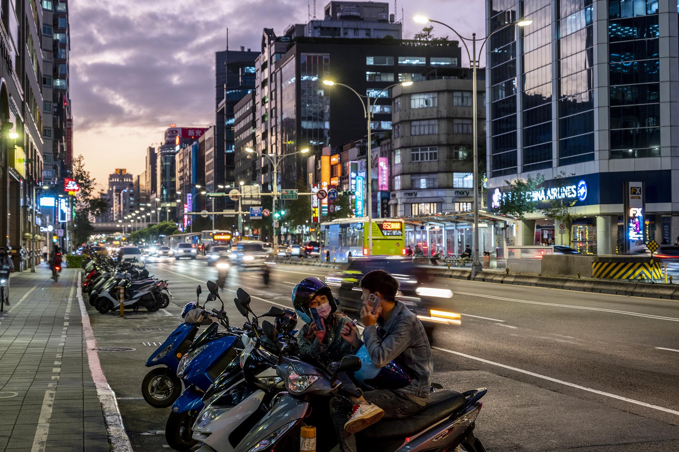 2022年11月19日，台北，年青人坐在机车上聊天。