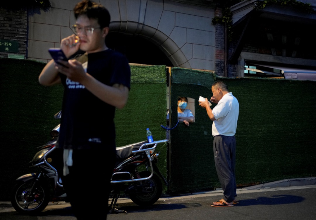 2022年7月11日，中國上海，一名圍在封小區內的居民與區外的市民交談。