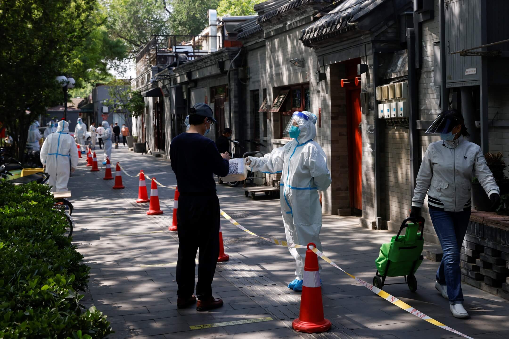 2022年5月3日，中国北京，一名穿保护衣的防疫人员要求一名前往进行核酸检测的居民先扫一个二维码。