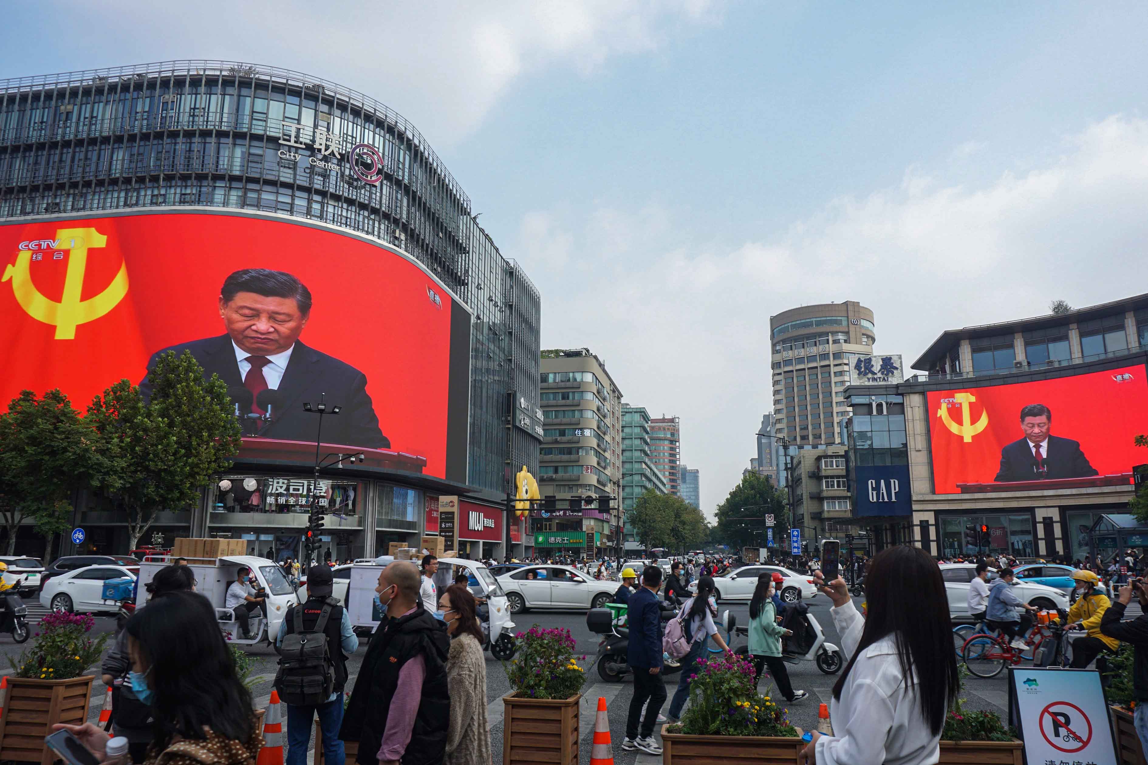 2022年10月23日，杭州，人们经过一个十字路口，巨大的屏幕播放习近平在共产党第二十次全国代表大会闭幕式上的讲话。