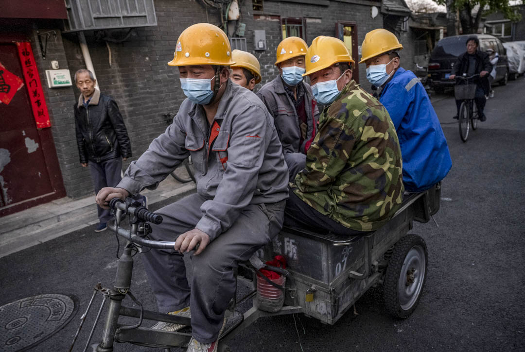 2021年4月14日，中國北京的建築工人騎著三輪車在街上行走。