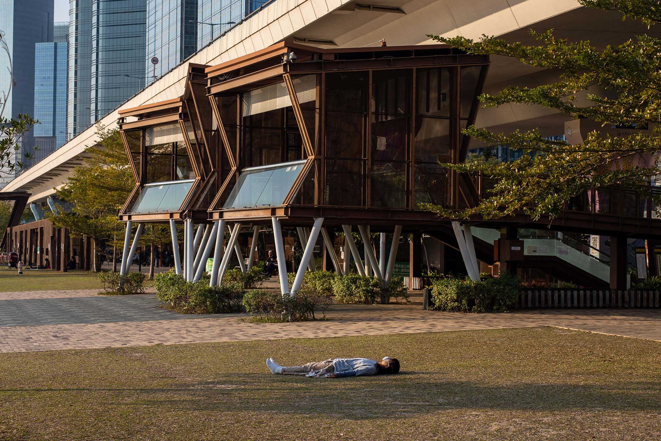 2022年3月3日，一名戴著口罩的人躺在香港观塘海滨长廊的草地上。