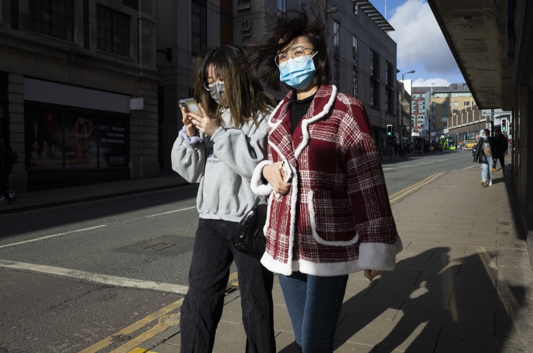 2022年2月9日，英国列斯市，两名戴口罩的女子在街道上走过。