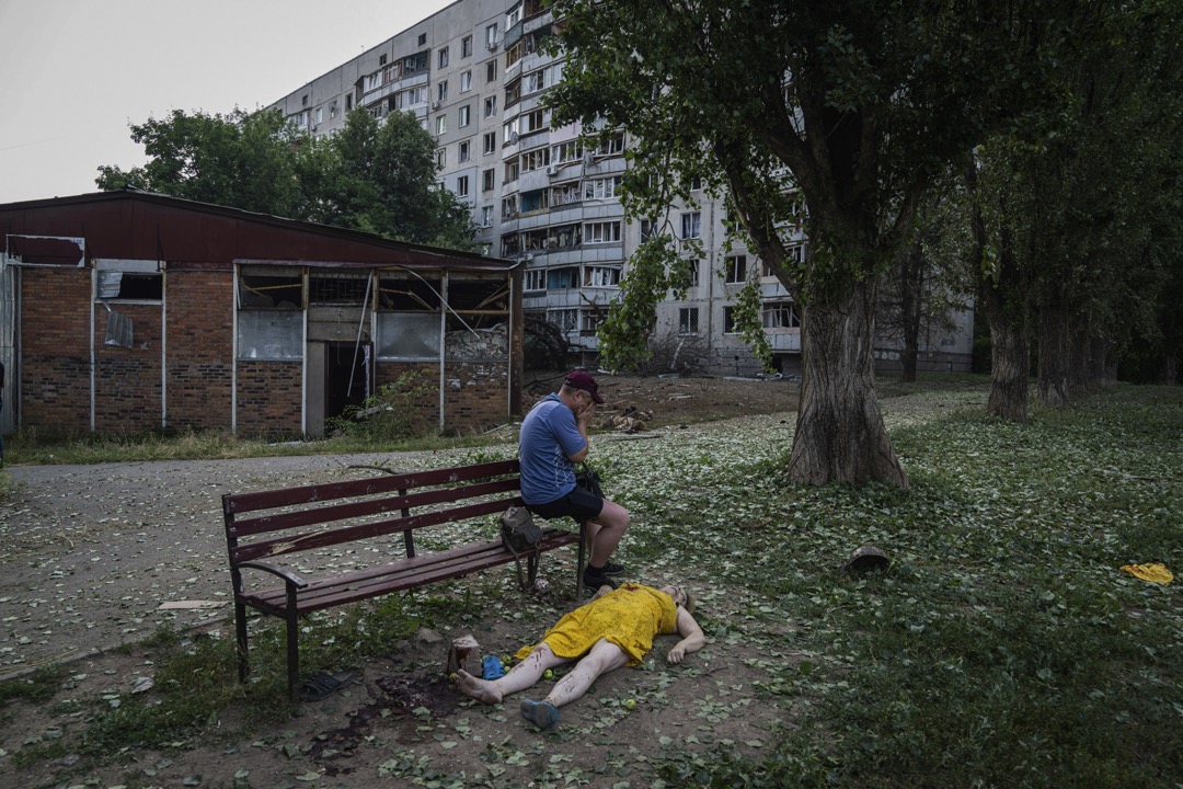 2022年7月7日，乌克兰哈尔科夫，一名男子坐在一名女子的遗体旁哭泣。摄：Evgeniy Maloletka/AP/达志影像