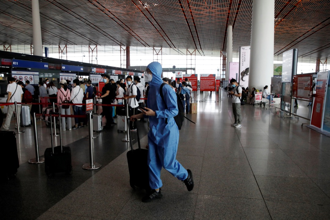 2020年6月17日，中国北京首都机场，一名穿保护衣的旅客在机场大堂走过。