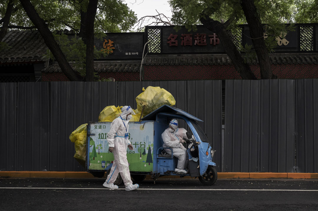 2022年6月28日，北京穿著防護服的環衛工人沿著隔離柵欄將垃圾帶走，