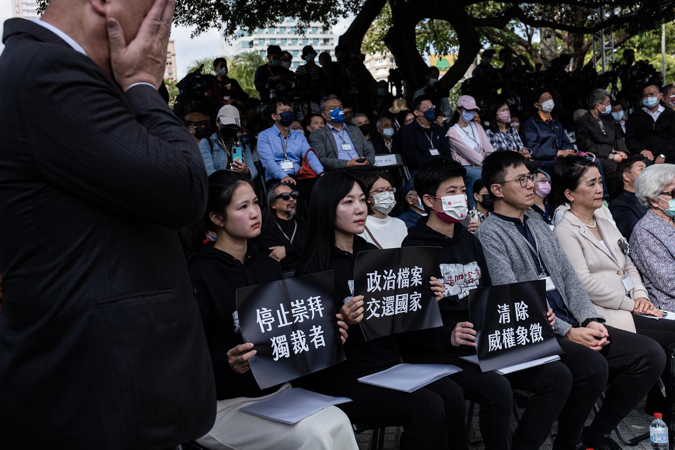 2023年2月28日，台北二二八和平纪念公园，台北市议员林亮君、吴沛忆、苗博雅等人，穿上“谁是加害者”的黑衣，出席台北市二二八纪念仪式，并分持“清除威权象征”、“停止崇拜独裁者”、“政治档案交还国家”的黑色纸板，坐在贵宾席上。