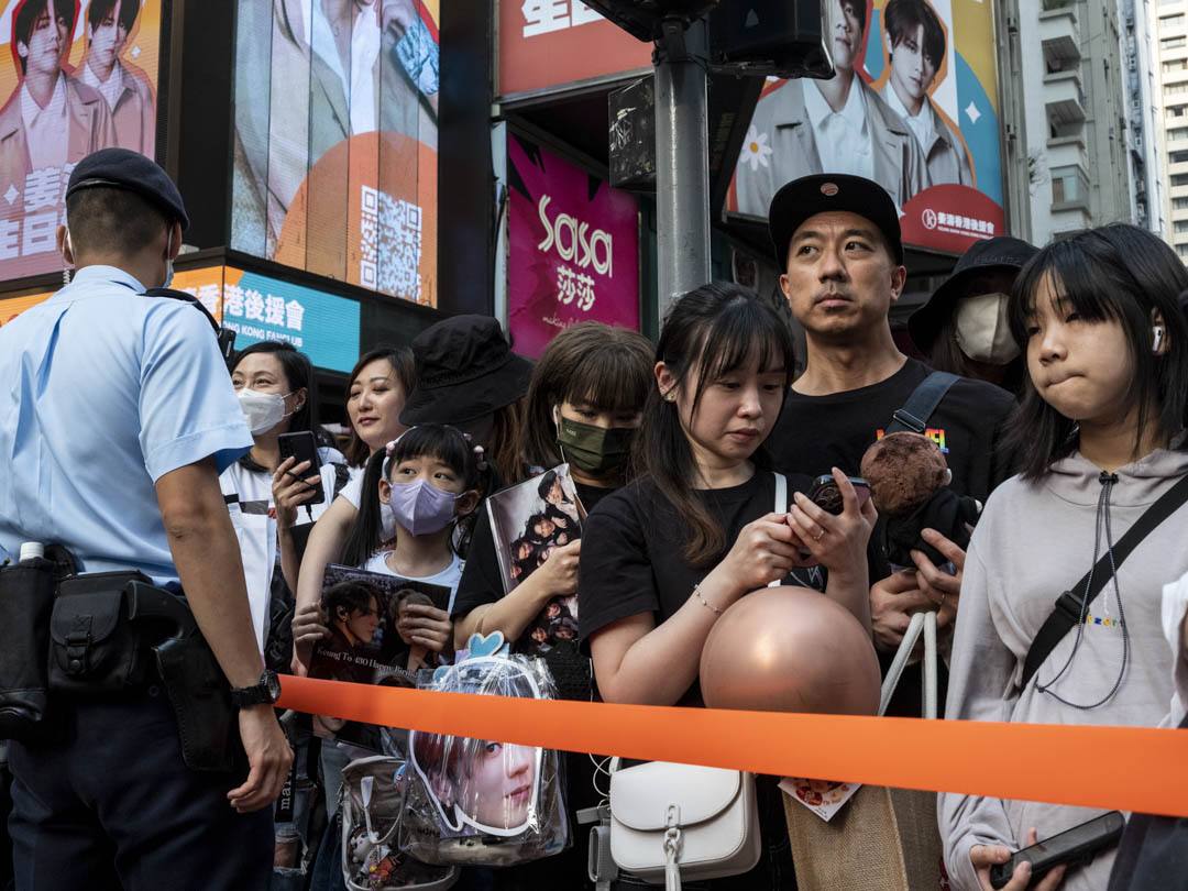 2023年5月1日，香港樂團Mirror的姜濤24歲生日，過萬名粉絲聚集在銅鑼灣的路旁，等待「姜濤號」電車，警察拉起橙帶以防他們衝出馬路。攝：林振東/端傳媒