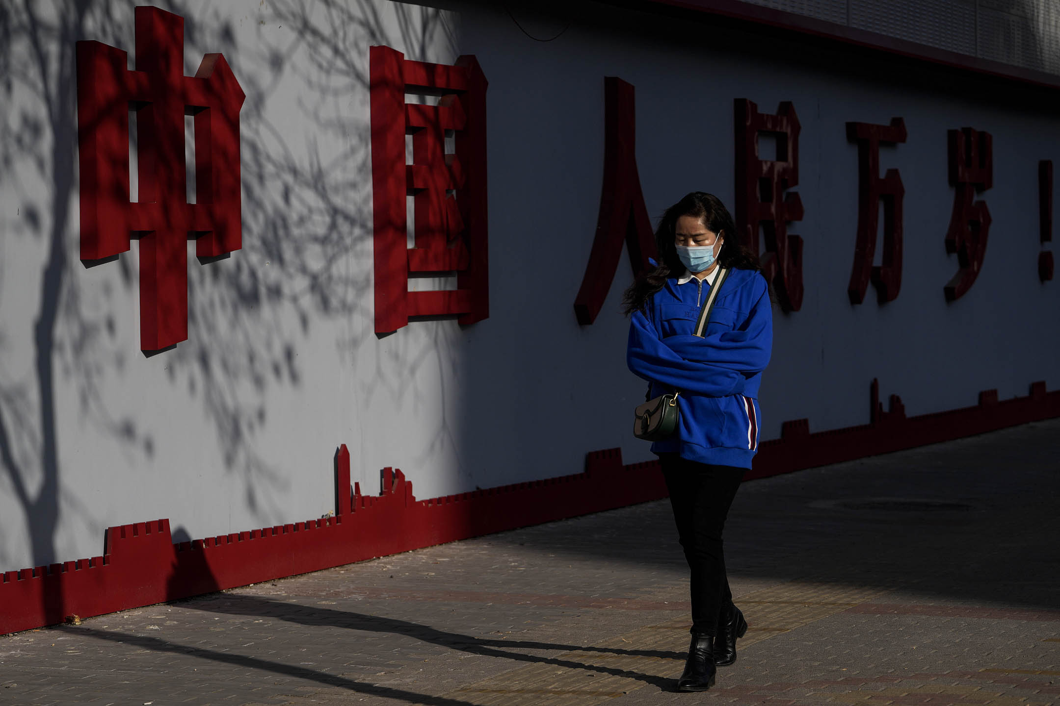 2023年3月2日，北京，戴着口罩的女士走过一幅写着“中国万岁”字样的墙。摄：Andy Wong/AP/达志影像