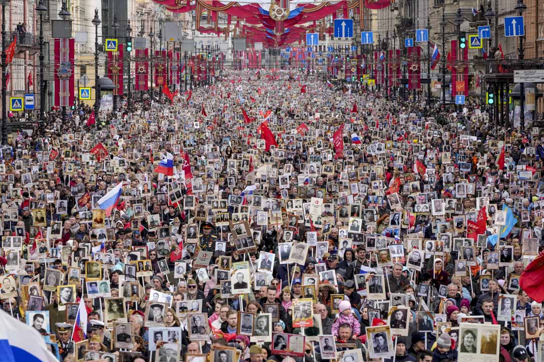 2022年5月9日，俄罗斯圣彼得堡中央大道涅瓦大街的不朽军团游行期间，人们举著参加过二战的亲属画像，以纪念第二次世界大战结束 77 周年。摄：Dmitri Lovetsky/AP/达志影像