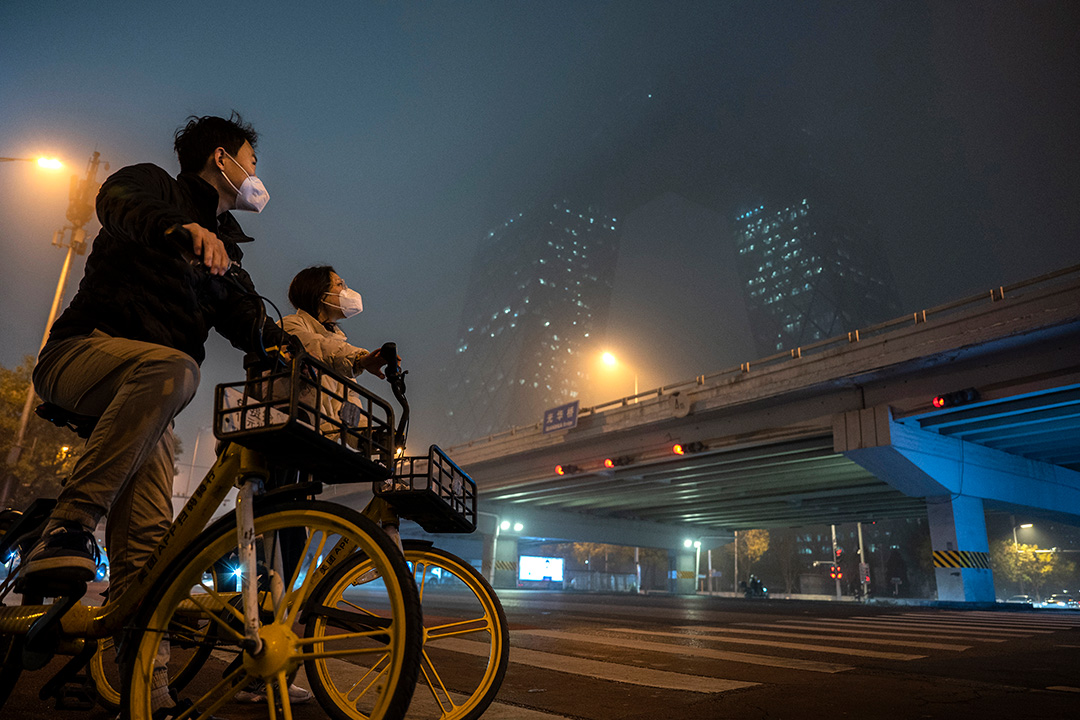 2022年11月20日，一对情侣望向被被雾霾笼罩的高楼大厦。摄：Kevin Frayer/Getty Images